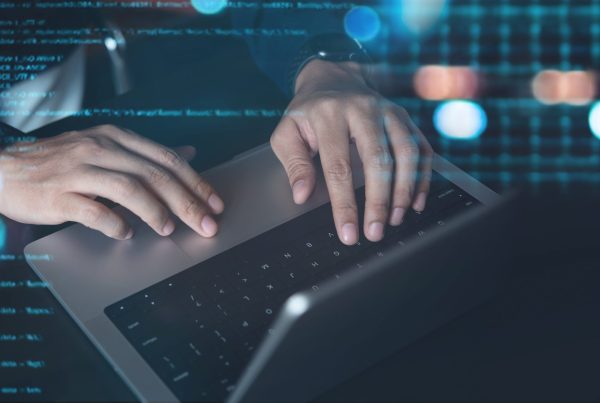 Man with hands on laptop - coding with AI